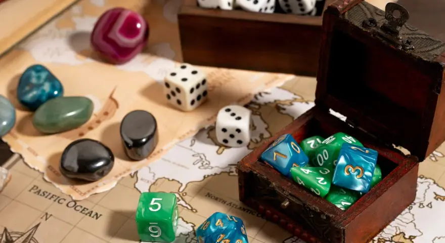 Dadi colorati e pietre preziose su una mappa antica, pronti per i migliori giochi da tavolo.