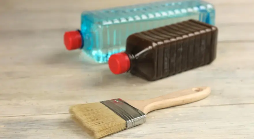 Pennello e due bottiglie: una con liquido blu, l'altra marrone. Capire la differenza tra acquaragia e diluente è fondamentale per i lavori di pittura.