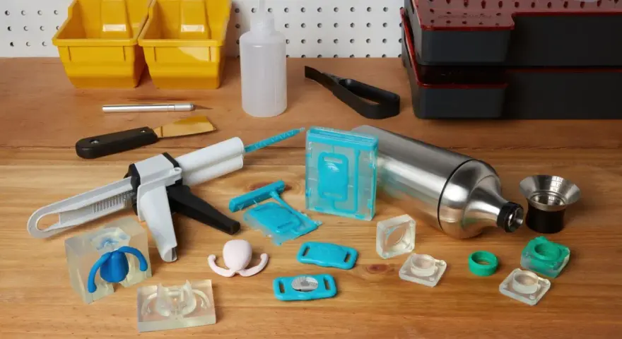 Attrezzi per la lavorazione della resina, inclusi stampi in silicone, pistola per colla e contenitori, utili per capire come pulire gli stampi in silicone dalla resina.
