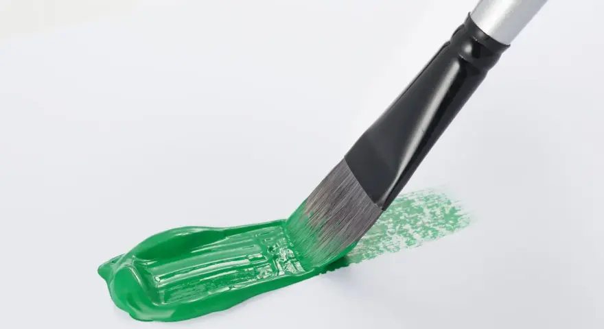 Pennello stende un brillante verde acrilico su carta bianca, creando un'opera d'arte fai da te.