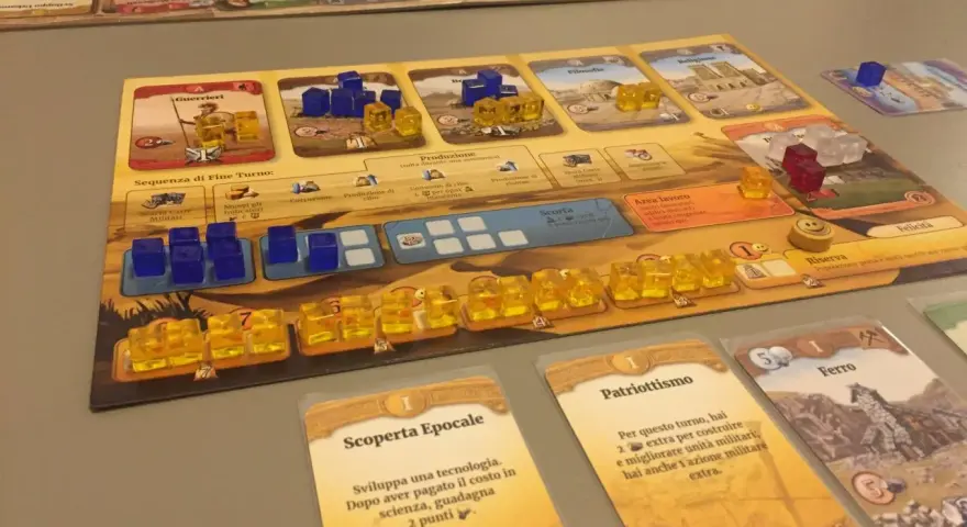 Un gioco da tavolo che ripercorre le ere, con pedine blu e gialle che rappresentano risorse e unità, carte evento e un tabellone di civiltà.