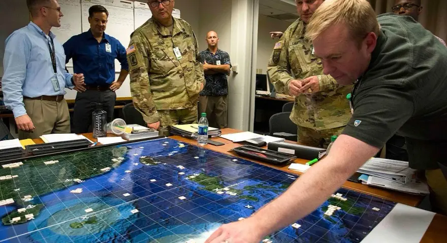 Uomini in uniforme e civili studiano un grande gioco da tavolo strategico con armate e territori marittimi, pianificando mosse.