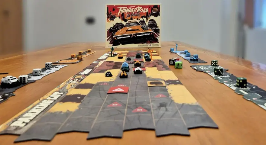 Il gioco da tavolo "Thunder Road Vendetta" è pronto per una folle corsa. Dadi e macchinine colorate sul tavolo.
