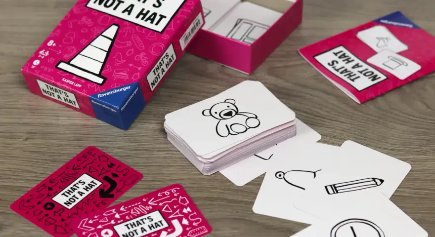 Scatola e carte del gioco "That's Not a Hat" con disegni di orsacchiotti, matite e orologi.