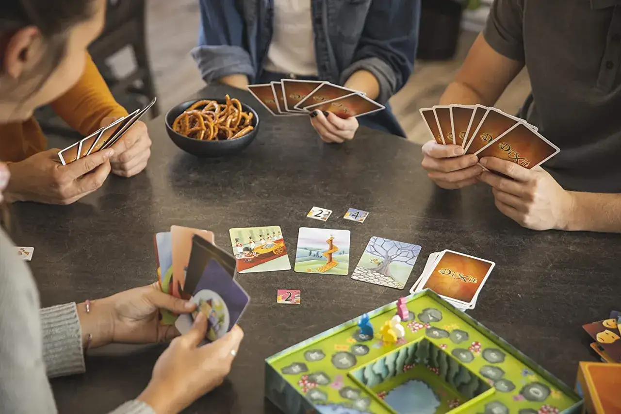 Amici riuniti attorno a un tavolo per divertenti giochi sociali, carte colorate e salatini.