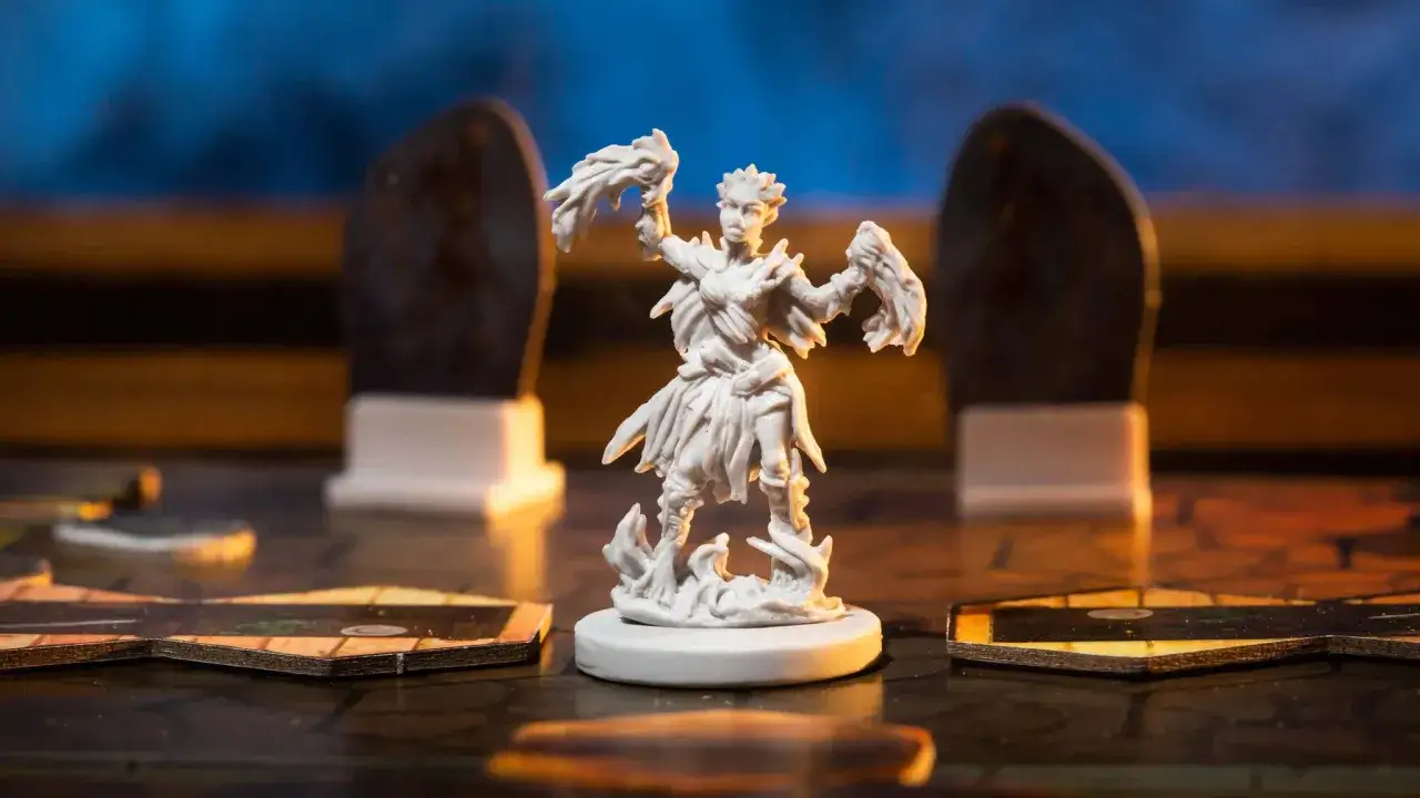 Miniatura di un personaggio scheletrico con fiamme nelle mani, su un tabellone di gioco. Un assaggio di Gloomhaven recensione.