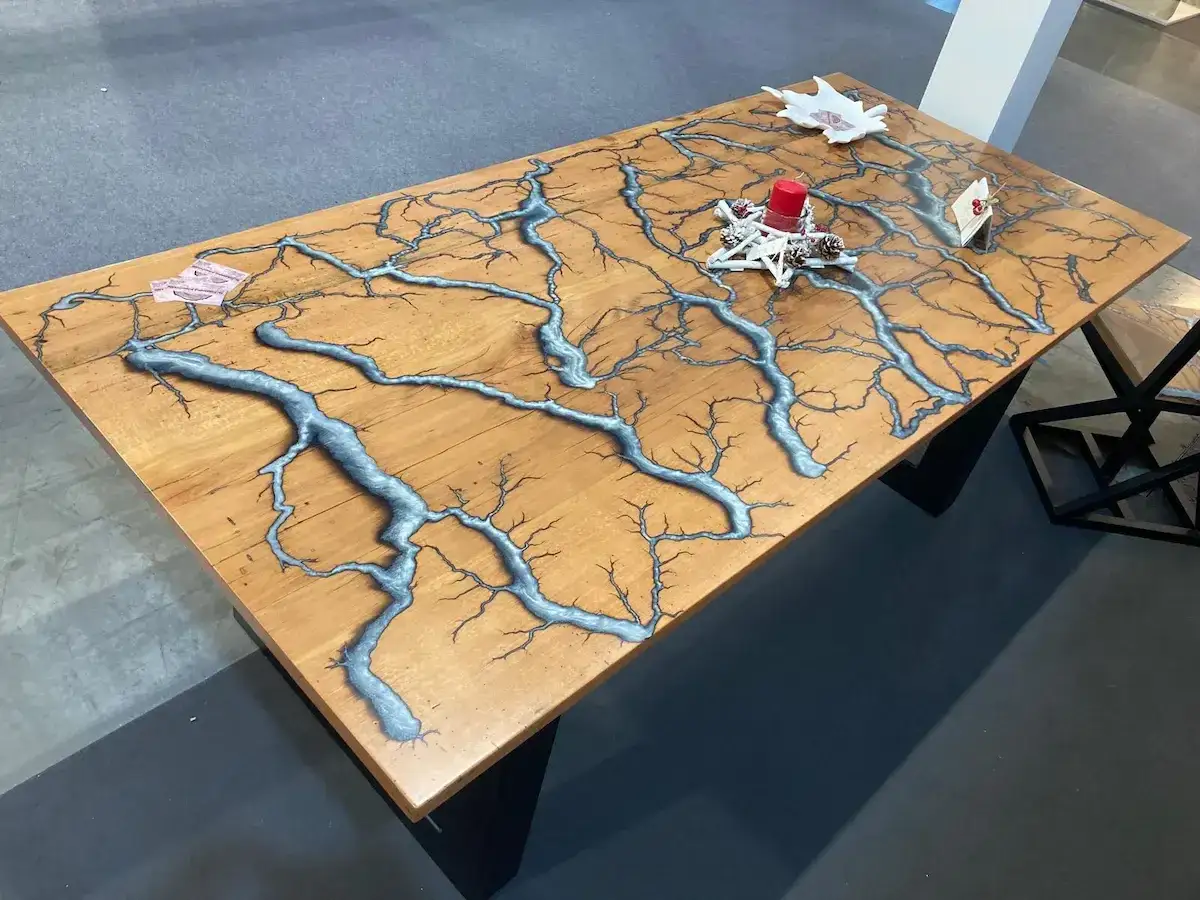 Tavolo in legno con venature blu metallizzato che ricordano fulmini, un esempio di come si fa la resina per creazioni uniche.