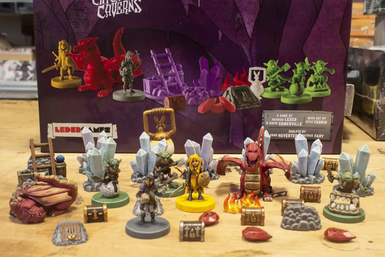 Vasto gioco da tavolo con miniature di draghi, goblin, avventurieri e tesori, pronto per epiche avventure nelle caverne.