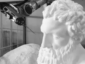 Un braccio robotico con una punta da trapano si avvicina a un busto di polistirolo, suggerendo un metodo innovativo per come sciogliere il polistirolo.
