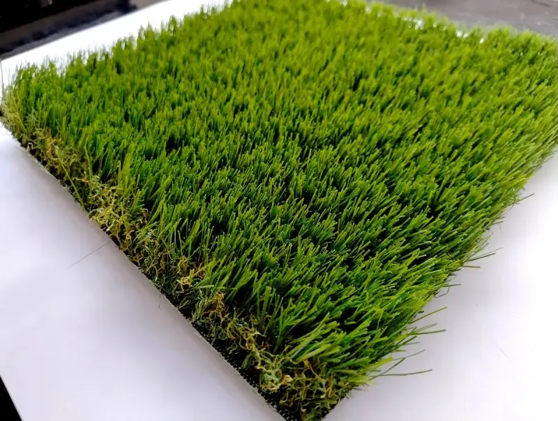 Un campione di erba sintetica, verde brillante e folta, mostra come fare l'erba finta per un giardino perfetto.